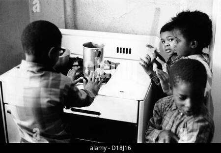 African American Kinder vier Cluster rund um den Gasherd für Wärme. Die unzureichende Heizung in ihrer Wohnung in Harlem Stockfoto