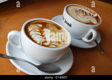 zwei Tassen Kaffee mit blumigen Dekorationen auf Schaum Stockfoto