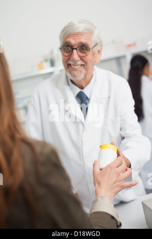 Lächelnde männlichen Apotheker zeigt auf eine Schachtel mit Pillen Stockfoto