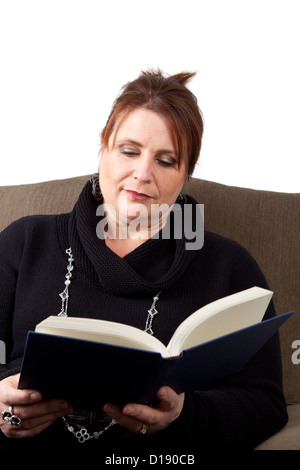 Eine scharf gekleidete mittlere gealterte Frau entspannt sich in einen Sessel und liest. Stockfoto