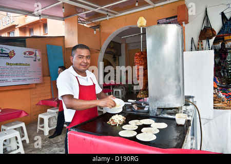 Mexikanische Jüngling machen traditionelle Tacos al Pastor vom Drehspieß angepresst Schweinefleisch rotierenden spucken La Crucecita Huatulco, Mexiko Stockfoto