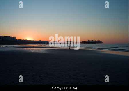 Mann allein zu Fuß am Strand bei Sonnenaufgang, Brighton Pier, Ebbe Stockfoto