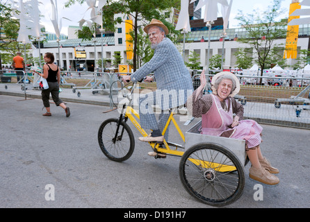 Komiker gekleidet und als ein älterer Mann mit seiner Frau in ein Dreirad. Stockfoto