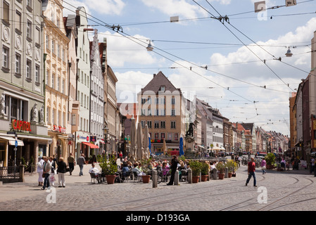 Stadtzentrum Straßenszene mit obenliegenden Straßenbahnlinien und Menschen Essen im Freien in Straßencafés in Augsburg, Bayern, Deutschland Stockfoto