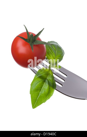 Cherry-Tomaten und Basilikum Blätter auf einer Gabel auf einem weißen Hintergrund Stockfoto