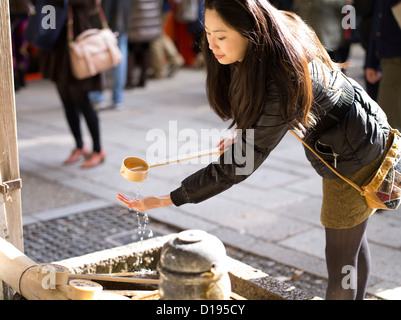 Japanische Frau besuchen Fushimi Inari-Taisha ein Shinto-Schrein mit orange Torii Toren in Kyoto, Japan. Reinigung der Hände bei Schriftart Stockfoto