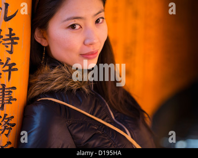 Japanese woman visiting Fushimi Inari Taisha a shinto shrine with orange torii gates in Kyoto, Japan. Stockfoto