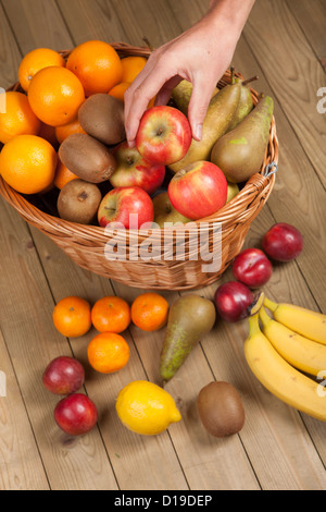 Hand einen Apfel aus Korb abholen Stockfoto