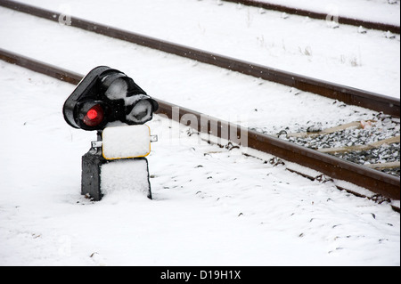 Eine rote Ampel-Signal in der Nähe ein Bahngleis mit Schnee bedeckt Stockfoto