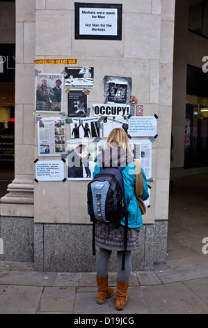 Eine Frau liest, dass Plakate ausgehängt besetzen London antikapitalistischer Demonstranten in der Nähe ihrer Protest-Camp außerhalb St. Pauls Cathedral. Stockfoto