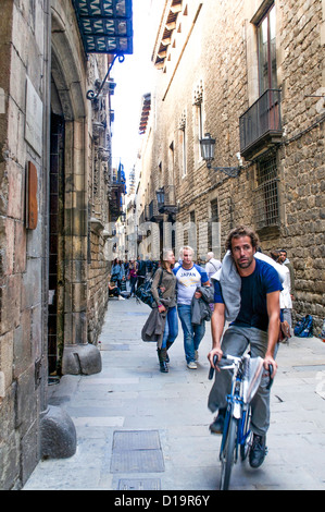 Radfahrer & Touristen buhlen um Platz in den engen mittelalterlichen Gassen des Barri Gotic Bezirk von Barcelona, Spanien. Stockfoto