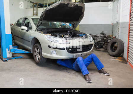 Männliche Mechaniker arbeiten unter dem Auto Stockfoto