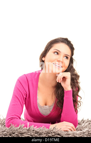 Eine lächelnde Frau liegend auf einem Teppich und denken isoliert auf weißem Hintergrund Stockfoto