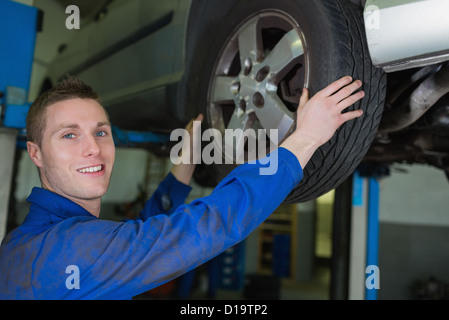 Männliche Mechaniker arbeiten am Rad des Autos Stockfoto