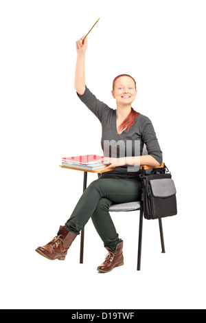 Eine Studioaufnahme an einer Studentin auf einem Stuhl sitzend und hob ihre Hand auf weißen Hintergrund isoliert Stockfoto