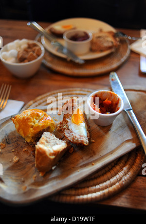 Teller mit hausgemachten Wurstbrötchen Schweinebraten und ein scotch Egg serviert in einem Café zum Mittagessen serviert Holzbrett Stockfoto