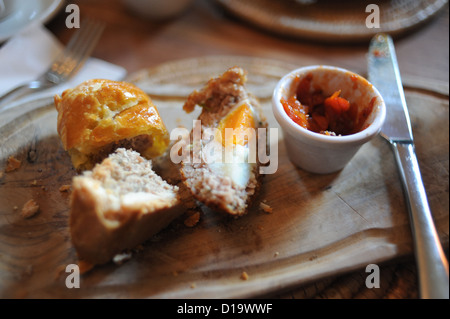 Teller mit hausgemachten Wurstbrötchen Schweinebraten und ein scotch Egg serviert in einem Café zum Mittagessen serviert Holzbrett Stockfoto