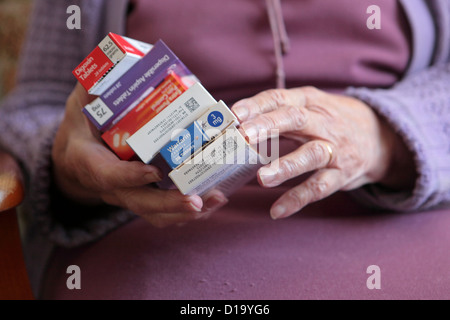 Ältere Frau an im Hause mit verwirrenden Reihe von verschiedenen täglichen Medikamente, Suffolk, UK Stockfoto