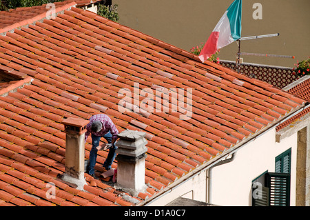 Italien; Toskana; Cortona; Mann Reparatur Ton-Ziegel-Dach, italienische Flagge Stockfoto