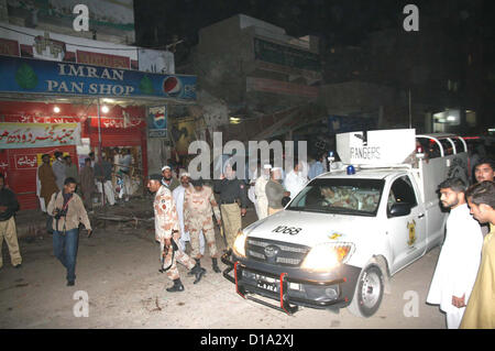 Menschen und Sicherheit Beamte sammeln am Standort nach Bombenanschlag in einem Teegeschäft, Landhi Bereich in Karatschi am Mittwoch, den 12. Dezember 2012.Two Menschen getötet, darunter ein Polizeibeamter, nach Bombe Abgang im Kader (BDS) Bombe war Fernbedienung und in Tabelle Stockfoto