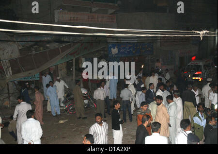 Menschen und Sicherheit Beamte sammeln am Standort nach Bombenanschlag in einem Teegeschäft, Landhi Bereich in Karatschi am Mittwoch, den 12. Dezember 2012.Two Menschen getötet, einschließlich ein Polizeibeamter nach Bombe Abgang im Kader (BDS) Bombe war Fernbedienung und in Tabelle platziert. Stockfoto