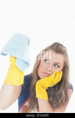 Gelangweilte junge Magd im gelben Handschuhe mit Staubtuch Stockfoto