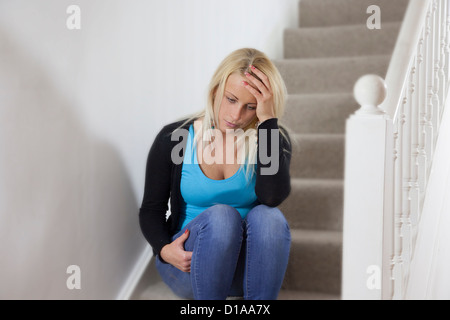 Junge Frau depressiv, allein auf der Treppe Hand am Kopf sitzen. Landschaft-Form. Stockfoto