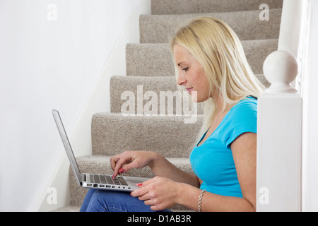 Lächeln Sie blonde Mädchen sitzen auf der Treppe mit einem Laptop, sanften. Seitenansicht, Landschaft Form. Stockfoto