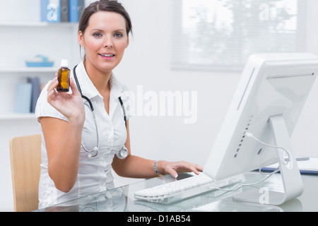Porträt der Ärztin hält Medizinfläschchen vor computer Stockfoto