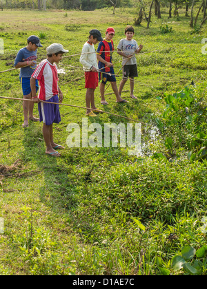 Fünf jungen paraguayischen halten ihre Angelruten, wie verbringen sie einen Sommertag versuchen zum Fang von einem Bach in der Nähe ihrer hom Stockfoto