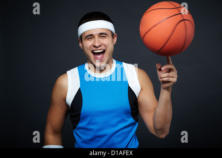 Porträt der lachende Mann in Sportbekleidung mit Basketball auf dem Zeigefinger, Blick in die Kamera Stockfoto