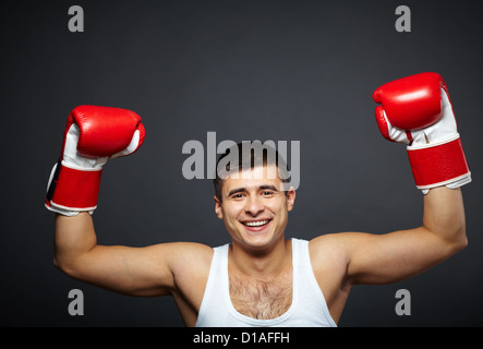 Porträt von glücklich junger Mann im roten Boxhandschuhe Blick in die Kamera Stockfoto