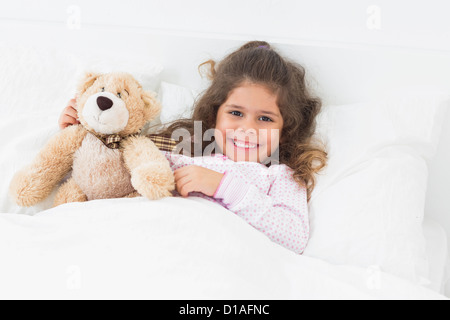 Kleines Mädchen mit Teddybär im Bett Stockfoto