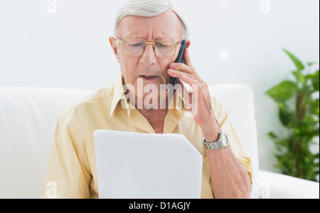 Älterer Mann Papiere auf dem Handy lesen Stockfoto