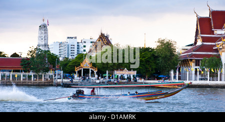 Ein Longtail-Boot Geschwindigkeiten vorbei die Tempelglocken auf dem Chao Phraya, Bangkok Stockfoto