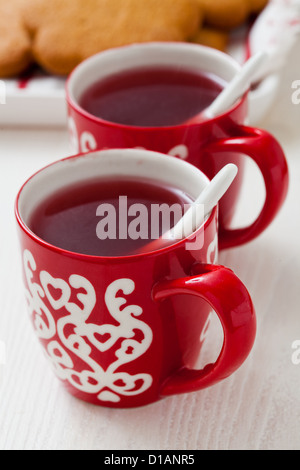 Weihnachten-Glühwein in zwei kleine rote Tassen und Lebkuchen vor weißem Hintergrund Stockfoto