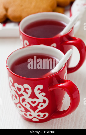Weihnachten-Glühwein in zwei kleine rote Tassen und Lebkuchen vor weißem Hintergrund Stockfoto