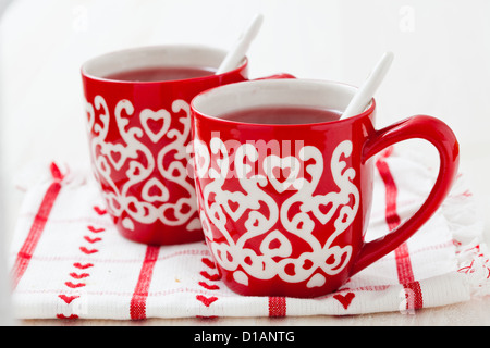 Weihnachten-Glühwein in zwei kleine rote Tassen ruht auf Teatowel vor weißem Hintergrund Stockfoto