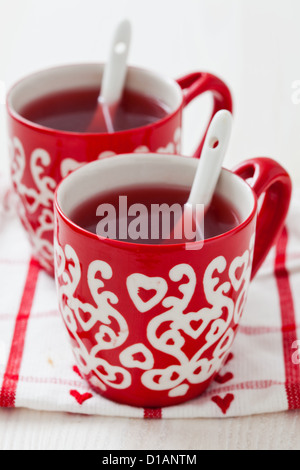 Weihnachten-Glühwein in zwei kleine rote Tassen ruht auf Teatowel vor weißem Hintergrund Stockfoto
