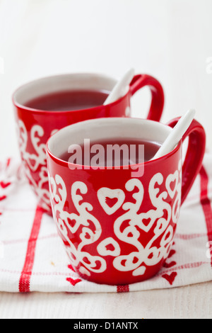 Weihnachten-Glühwein in zwei kleine rote Tassen ruht auf Teatowel vor weißem Hintergrund Stockfoto