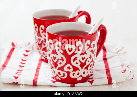 Weihnachten-Glühwein in zwei kleine rote Tassen ruht auf Teatowel vor weißem Hintergrund Stockfoto