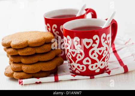 Nahaufnahme von Weihnachten Glühwein in zwei kleine rote Tassen und Lebkuchen vor weißem Hintergrund Stockfoto