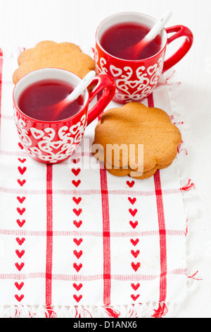 Weihnachten-Glühwein in zwei kleine rote Tassen und Lebkuchen ruht auf Teatowel vor weißem Hintergrund Stockfoto