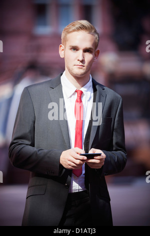 Porträt junger Geschäftsmann hält Handy Stockfoto