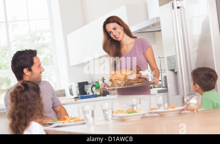 Mutter bringt Truthahnbraten auf Tisch Stockfoto