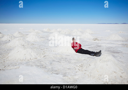 Mann sitzt neben Salzberge auf Salar de Uyuni (Salt Flats von Uyuni), Abteilung Potosi, Bolivien Stockfoto