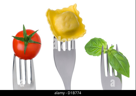 Essen Zutaten von Italien und italienische Küche. Ravioli, Kräuter Basilikum und Tomaten auf Gabeln vor einem weißen Hintergrund Stockfoto