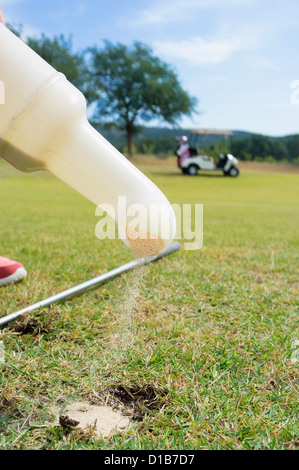Spieler füllt sich ein Divot auf einem Golfplatz Stockfoto