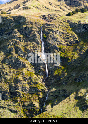 Ein Wasserfall fließt eine robuste Berghang in der Nähe von Skigebiet Treble Cone, Harris in den Bergen, in der Nähe von Wanaka, Neuseeland Stockfoto