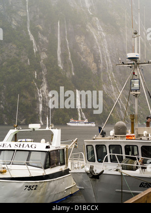 Blick auf den Milford Sound Wharf und Angelboote/Fischerboote an einem bewölkten, regnerischen Tag, Fjordland National Park, Neuseeland Stockfoto